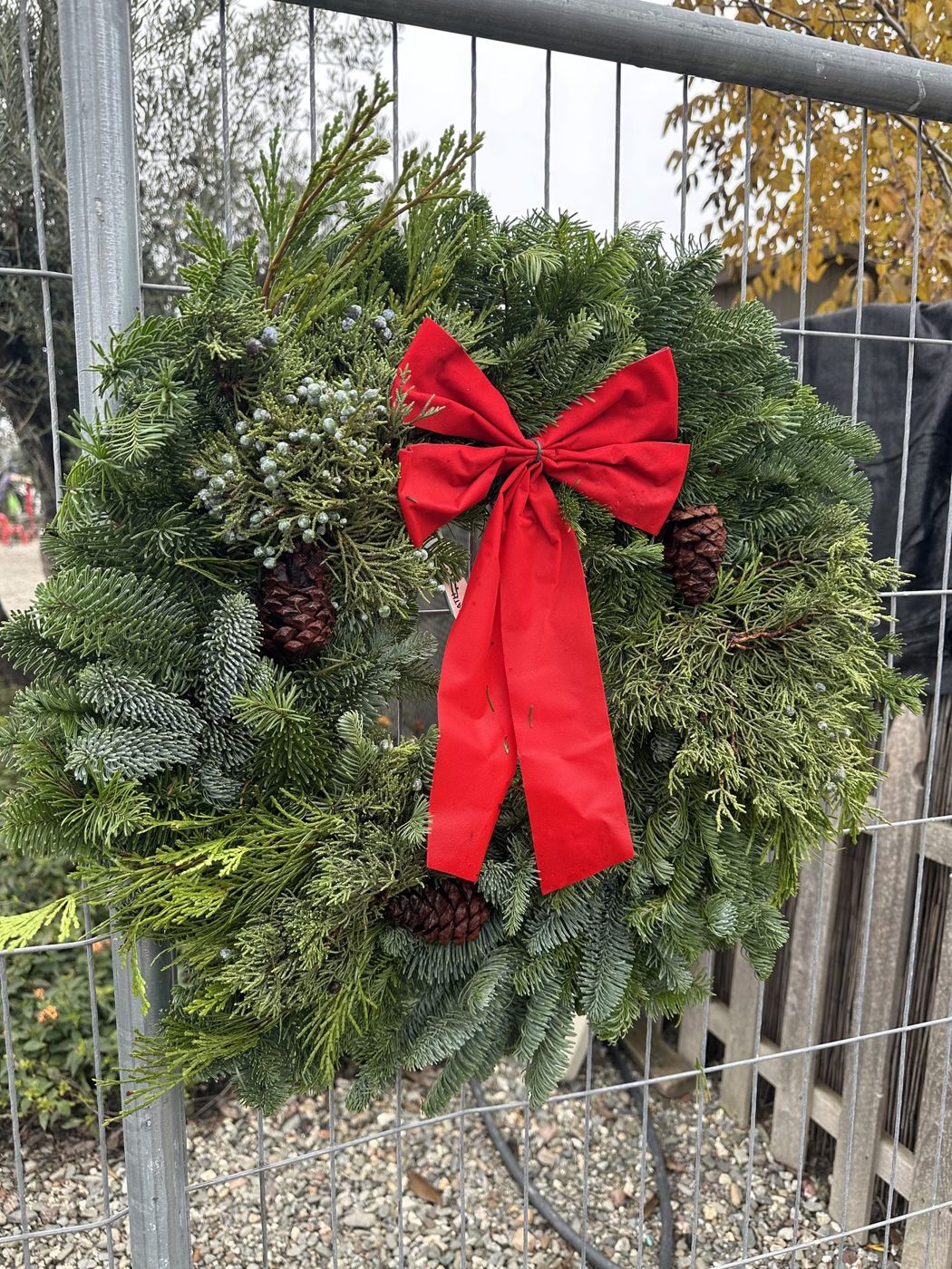 Fresh evergreen wreath with a red bow hanging on the fence at Country Christmas